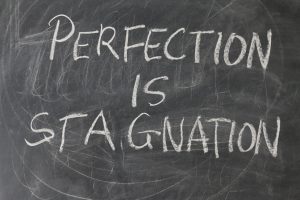 Tafel auf der steht dass Perfektion Stagnation ist das macht uns nicht glücklich