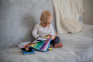Kleines Kind auf Sofa blaettert in Büchern und hat Lust Vokabeln nachhaltig zu lernen